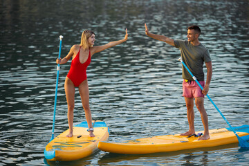 Woman and man surfing in ocean sea on surfboard, couple doing water sport.