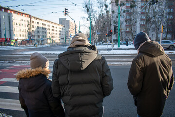 people waiting at a pedestrian crossing in winter