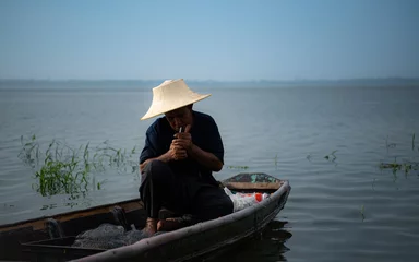 Foto op Canvas A fisherman relaxes in a boat on the lake while smoking. © Wosunan