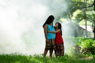 Two girls Asian women with traditional clothing stand had fun playing together in the rainforest. - obrazy, fototapety, plakaty