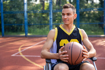 Basketball player man in wheelchair has disability playing on court, holding ball.