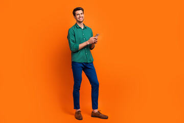 Full length body photo of cheerful businessman instagram targetologist ceo director company with phone isolated over orange color background