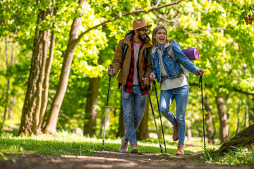 Obraz premium Young couple with scandinavian sticks walking and talking
