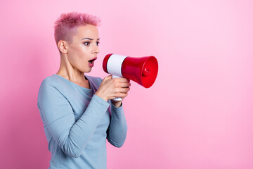 Photo of serious girl with short hair dressed blue sweatshirt look empty space shouting in loudspeaker isolated on pink color background