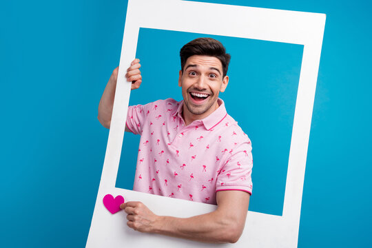 Portrait of funky excited man hold paper album card like notification heart isolated on blue color background
