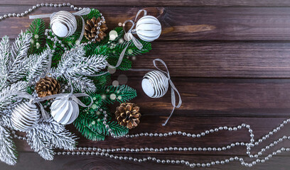 Christmas background with white Christmas balls, silver garland and pine cones. Festive composition on a dark wooden background.
