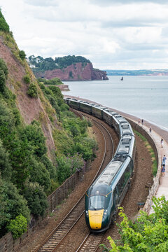 Devon, England – July 21, 2023: A Great Western Railway passenger train from London Paddington on the atmospheric route along the coast near Teignmouth UK