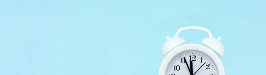 white analog alarm clock on blue background with copy space, business meeting schedule, travel...