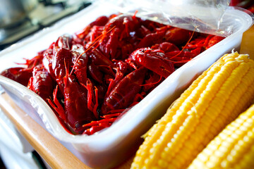 Louisiana crawfish in a tupperware container next to corn ready for seafood boil