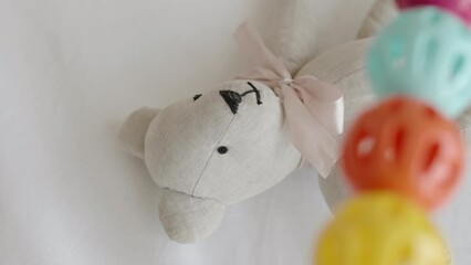 From above no people shot of cute toy bear and colorful rattles in white cozy baby crib