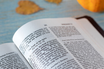 Fruit of the Spirit verses in open holy bible book with pumpkin and autumn leaves in the...