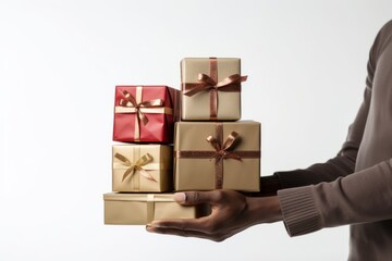 A person presenting stack of gift boxes standing against white backdrop