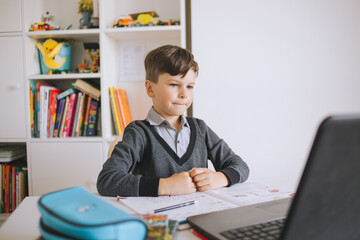 Distance learning online. A schoolboy boy studies at home. Child boy uses a laptop and communicates...