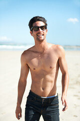Obraz premium Summer, sunglasses and the body of a man on the beach for travel, freedom or adventure on vacation. Nature, sand and a young person shirtless by the ocean or sea on a tropical coast for holiday