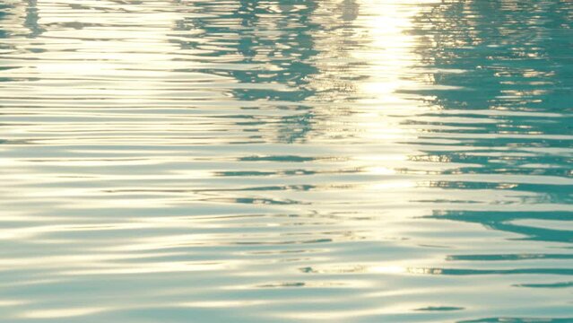At sunset time, the light reflects off the ripples of a crystal clear water