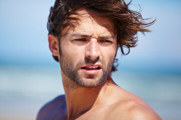 Face, idea and wind with a man on the beach for freedom, travel or vacation in summer. Nature, thinking and wellness with a shirtless young person at peace on the coast for a tropical holiday