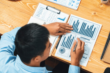 Fototapeta na wymiar Top view diverse group of business analyst team analyzing financial data report paper on meeting table. Chart and graph dashboard by business intelligence analysis. Meticulous