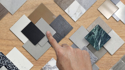 architect's hand picks samples of interior material contains ceramic tiles, artificial stones,...