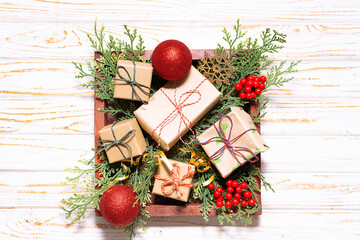 Wooden box with Christmas gifts, fir tree branches and traditional festive decorations on wooden rustic background top view.