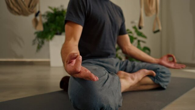 close-up of hands and fingers of man meditating in hall and sitting in lotus position man care
