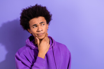 Fototapeta na wymiar Portrait of minded pensive young man arm touch chin look interested empty space ponder isolated on purple color background