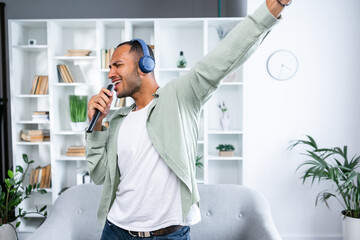 Excited man having fun listening to music and singing with headphones at home