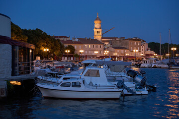 Port on the Adriatic Sea with the old town in the background in the Croatian city of Krk with moored boats in the evening time.
