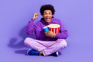 Full size photo of ecstatic person wear stylish pullover hold popcorn soda cup watch football match isolated on purple color background