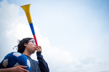 Woman holding blue soccer ball and using vuvuzela to support team in cloudy day