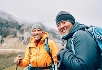 Deurstickers Makalu Caucasian and Sherpa men with backpacks together smiling at camera Makalu Barun Park trekking route. Mera peak climbing acclimatization walk. Backpackers using trekking poles, enjoying valley view.