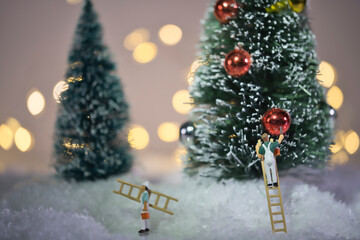 Painter with ladder painting the colorful balls on a huge Christmas tree, miniature figures scene