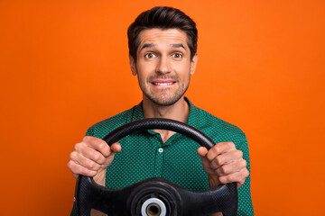 Photo of doubtful unsure guy wear green shirt biting lip driving auto isolated orange color background