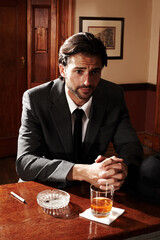 Portrait, thinking and man with whiskey, relax and bar with ideas, ashtray and glass with cigarette. Person, gentleman and smoker with alcohol, tobacco and wonder with peace, nicotine and thoughts