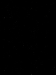 Festive vector background with gold glitter and confetti for christmas celebration. Black background with glowing golden particles.