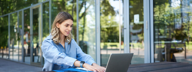 Portrait of businesswoman working with laptop. Corporate woman using computer outdoors, attend...