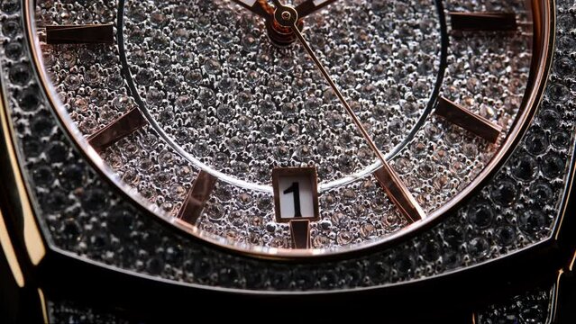 Extreme closeup of yellow second arrow passing by on diamond clock face. Lengthwise view of luxury swiss watch. Closeup real time shot. Running second arrow. expensive watch with diamonds