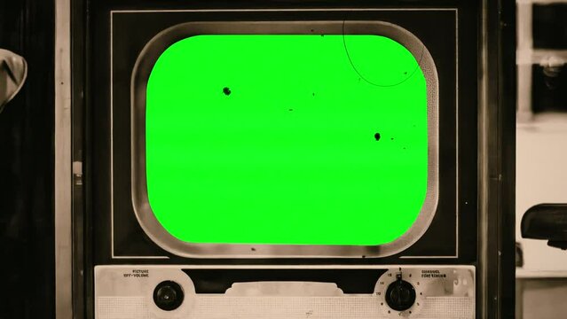 Retro TV Green Screen Old Film Texture Sepia Vintage Television Zoom In. Old vintage television with green screen, for replacement, inside a house, zoom in. Old sepia film texture