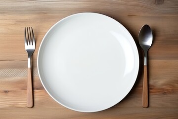 White ceramic plate and cutlery on wooden background
