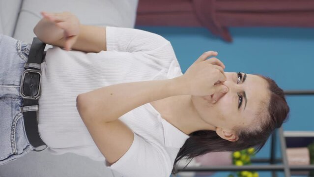 Vertical video of The young woman who smells bad odor is disturbed and disgusted.