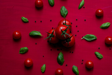 Fresh, red cherry tomatoes with green stems on red bckground