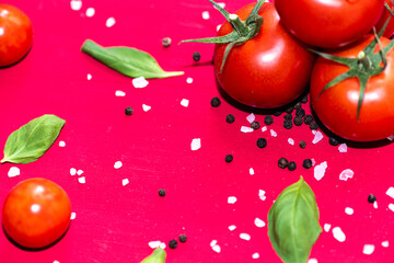 Fresh, red cherry tomatoes with green stems on red bckground