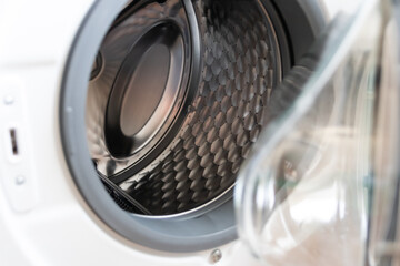 View into washing machine drum inside with stainless steel drum interior shows household equipment for cleaning clothes with dry cleaner and front loader for easy housework laundromat machine empty