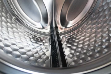 Fotobehang View into washing machine drum inside with stainless steel drum interior shows household equipment for cleaning clothes with dry cleaner and front loader for easy housework laundromat machine empty © sunakri