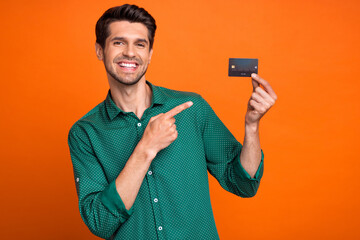 Photo of young man direct finger plastic credit payment card money maker create content for tiktok isolated on orange color background