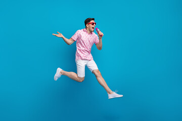 Full body portrait of energetic crazy young man jump hold microphone sing empty space isolated on...