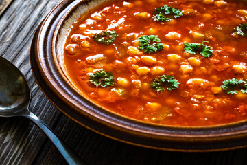 Moroccan cuisine - harira fresh vegetable soup with chickpeas and lentil on wooden table
