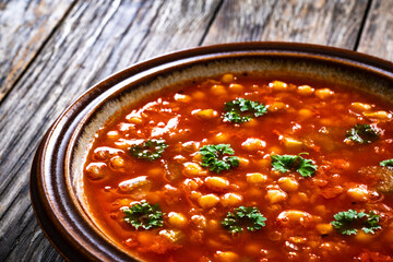 Moroccan cuisine - harira fresh vegetable soup with chickpeas and lentil on wooden table
