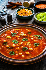 Moroccan cuisine - harira fresh vegetable soup with chickpeas and lentil on wooden table
