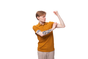 young strong student man with red hair and a tattoo on his arm is wearing a yellow t-shirt