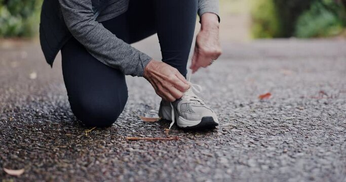 Running, shoes and hands of senior woman in a road for morning cardio, fitness or workout closeup. Zoom, shoelace and feet of elderly female athlete outdoor for training, exercise and run in nature